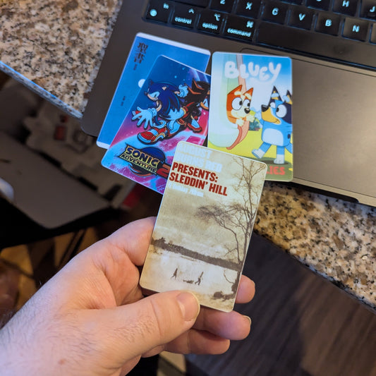 Hand holding an August Burns Red yoto card. Also pictured are Bluey, Sonic, and Japanese yoto cards.